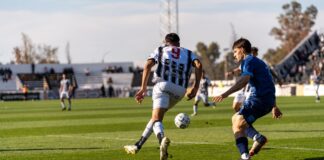 Players in action on the soccer field during an outdoor match under the bright sun.