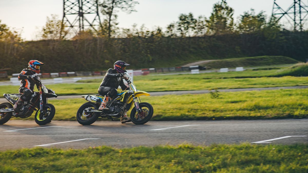 Two motorcyclists racing on an outdoor track, showcasing thrilling motor sport action.