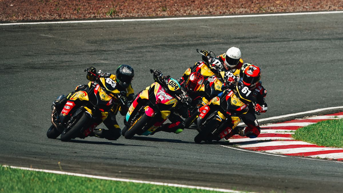 Dynamic shot of four motorcyclists racing on a curved track, showcasing speed and competition. Dynamic shot of four motorcyclists racing on a curved track, showcasing speed and competition.