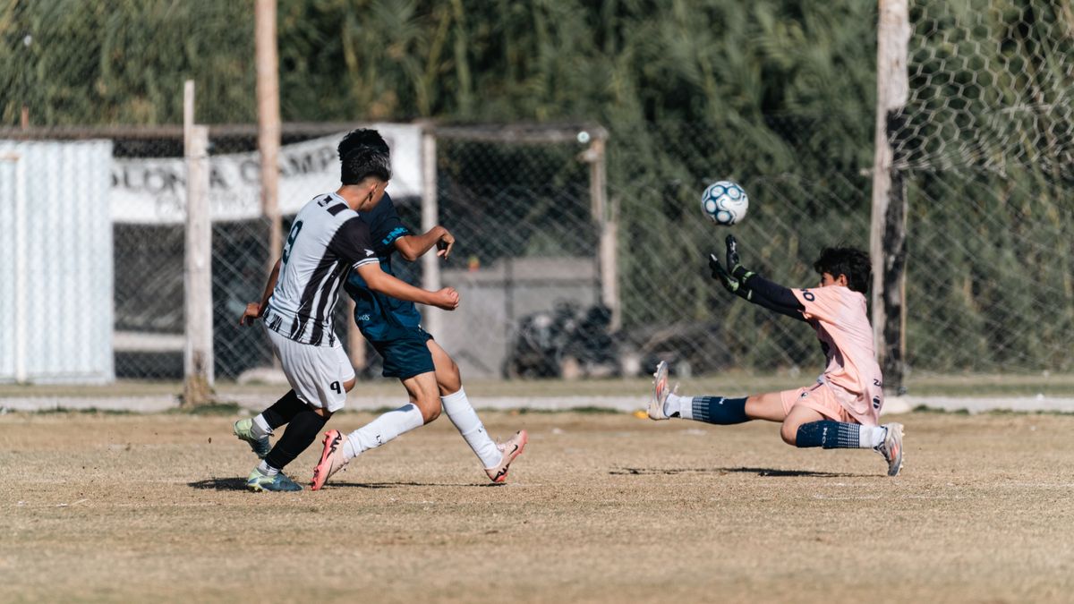 Football match action shot capturing a goalkeeper's dramatic save during a game.