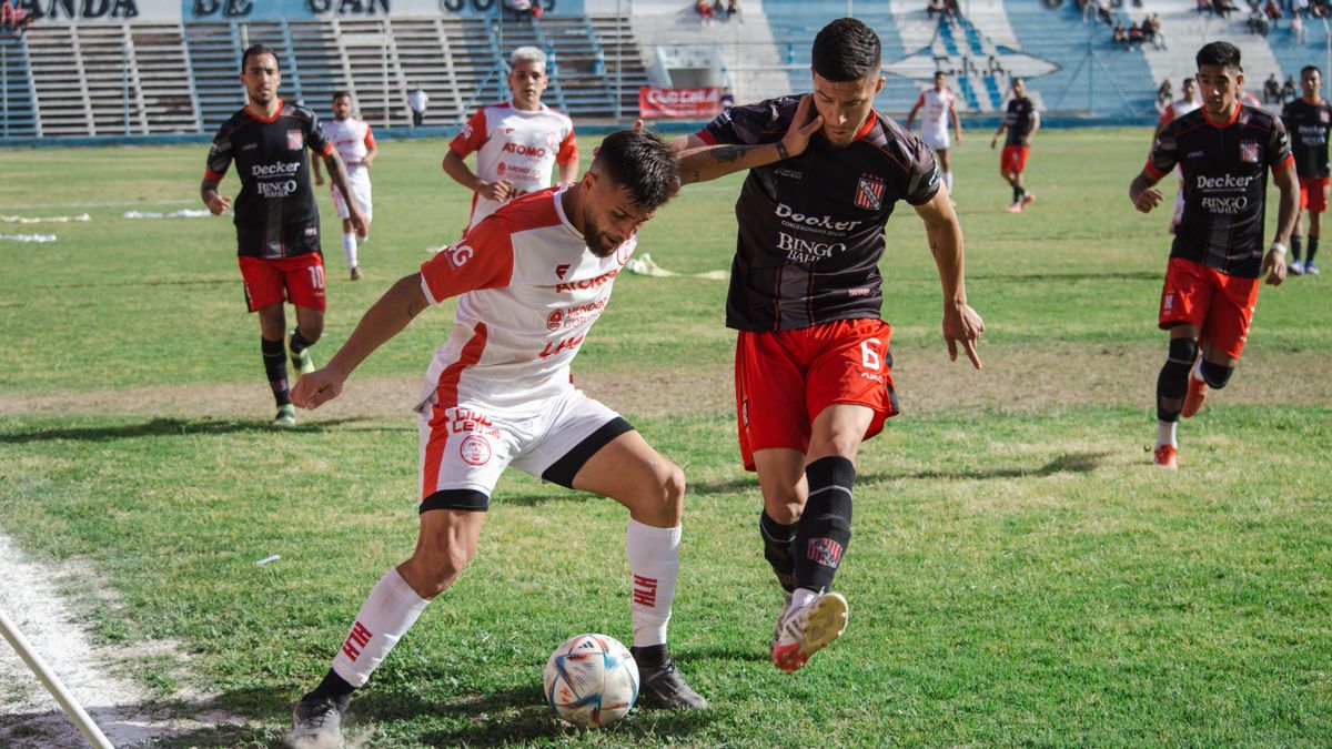 Competitive soccer match with players in action at an outdoor football field.