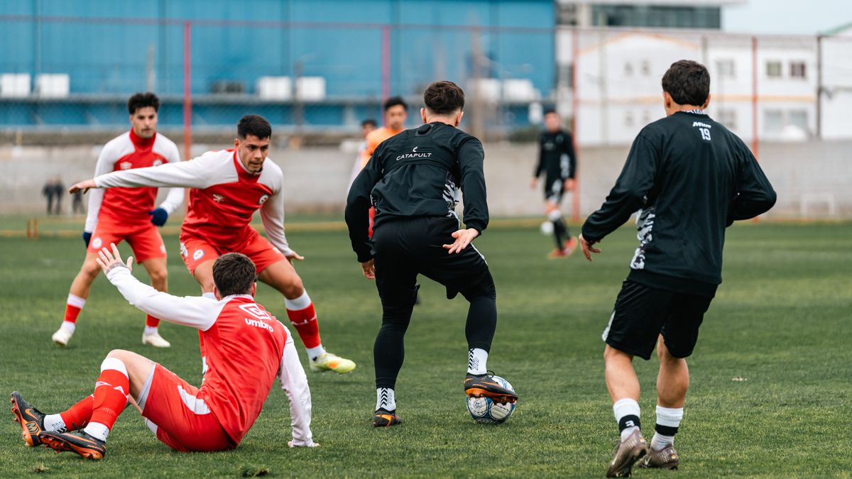 Group of soccer players practicing on a grassy field outdoors, showcasing teamwork and athletic skills.