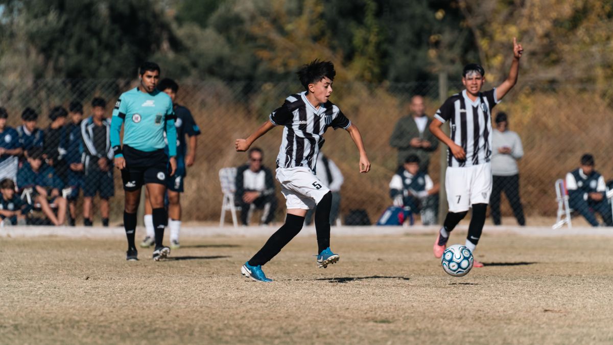 Teen soccer players in action during a competitive outdoor match on a grass field.