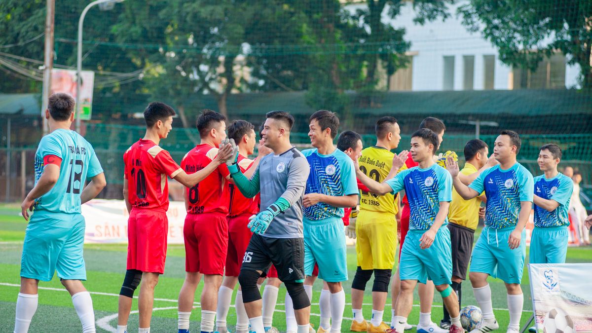 Two soccer teams shake hands on the field in Hanoi, showcasing sportsmanship.