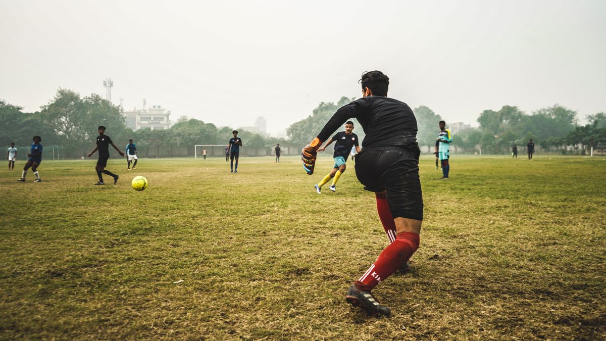 Energetic soccer game with players on a grassy field in India, showcasing teamwork and sportsmanship.