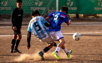 Intense soccer match action with two players competing for the ball on an outdoor field.