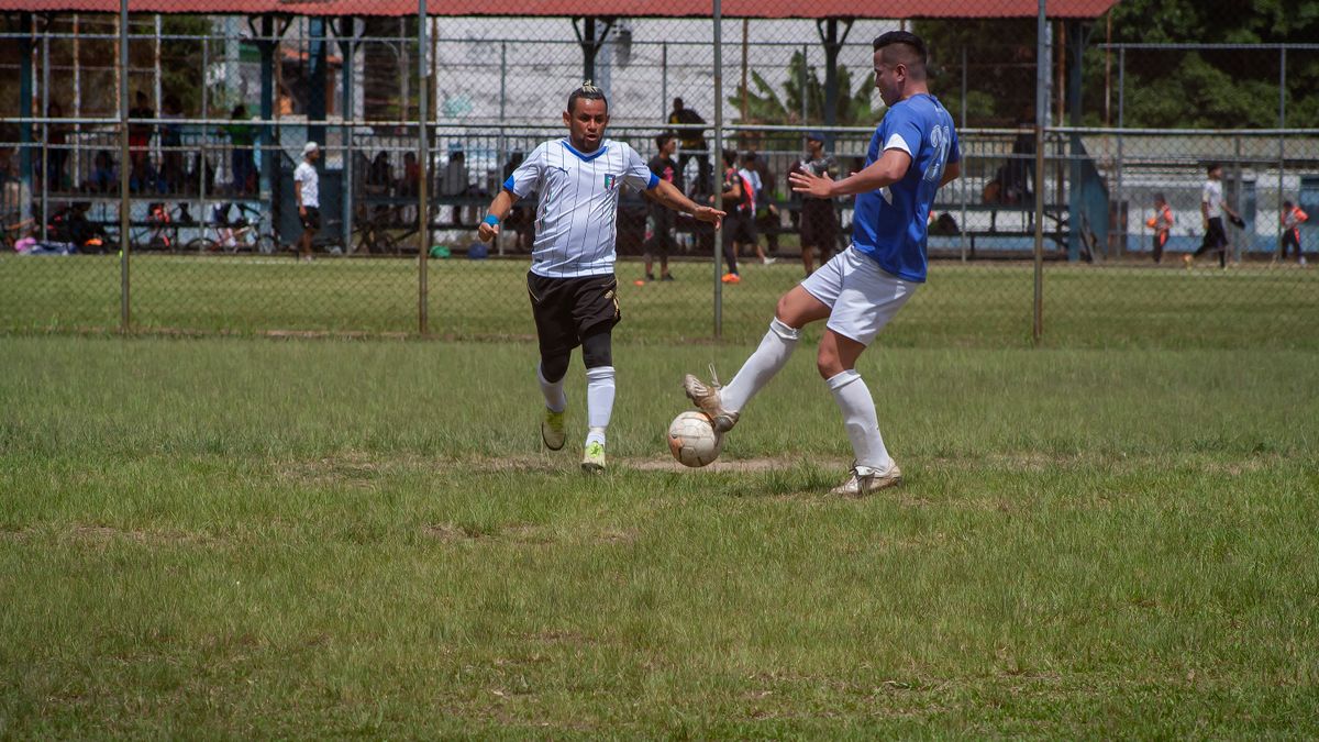 Two male soccer players competing in an outdoor match on a sunny day. Two male soccer players competing in an outdoor match on a sunny day.