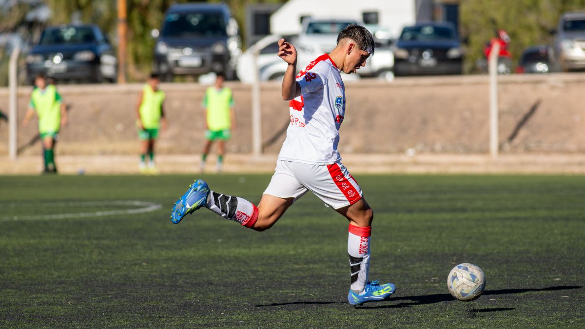 Young soccer player takes an athletic kick on an outdoor field during a match.