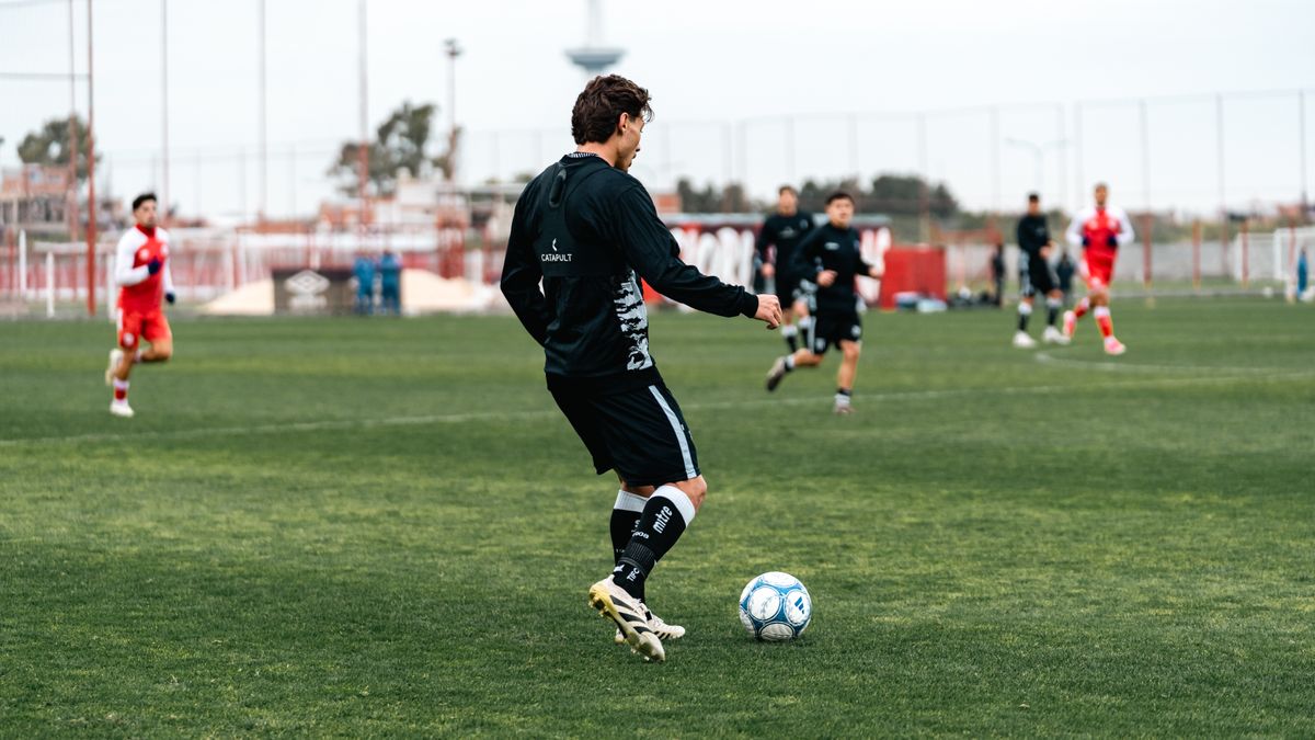 Soccer players in team practice on a grass field during the day.