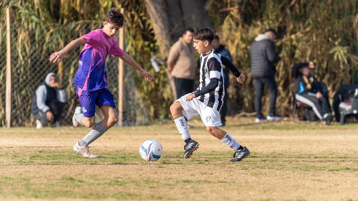 Teenage boys playing an intense soccer match outdoors on a sunny day.