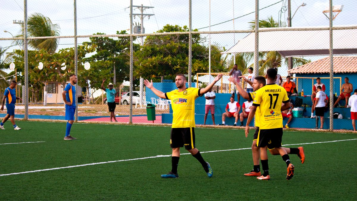 Amateur soccer team in yellow jerseys celebrates a goal during a match on an outdoor field.