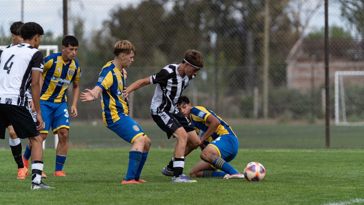 Dynamic action shot of a youth soccer game with players competing for the ball on a grassy outdoor field.