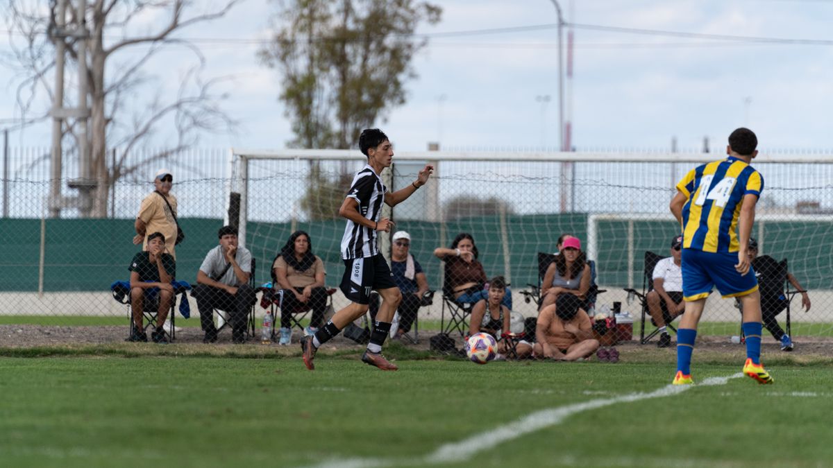 A lively teen soccer match with engaged spectators watching from the sidelines, outdoors.