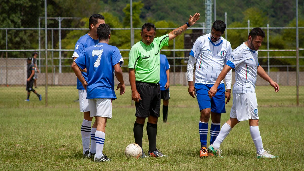 Soccer players and referee on a green field in Venezuela, mid-game action.