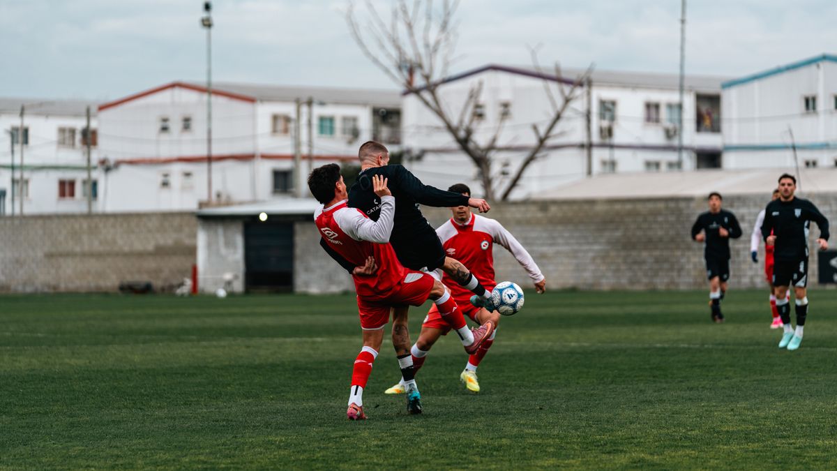 Soccer players engaged in a dynamic match outdoors on a grass field.
