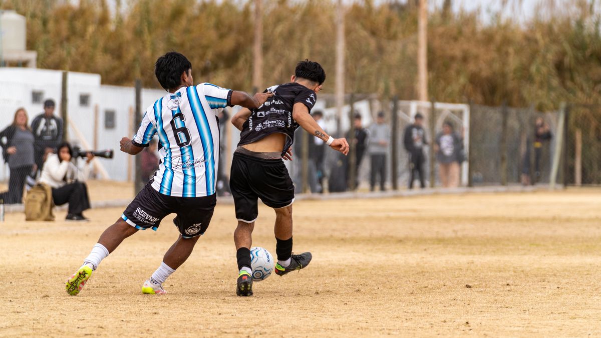 Soccer players in an intense match on a dry, dusty field surrounded by spectators. Soccer players in an intense match on a dry, dusty field surrounded by spectators.