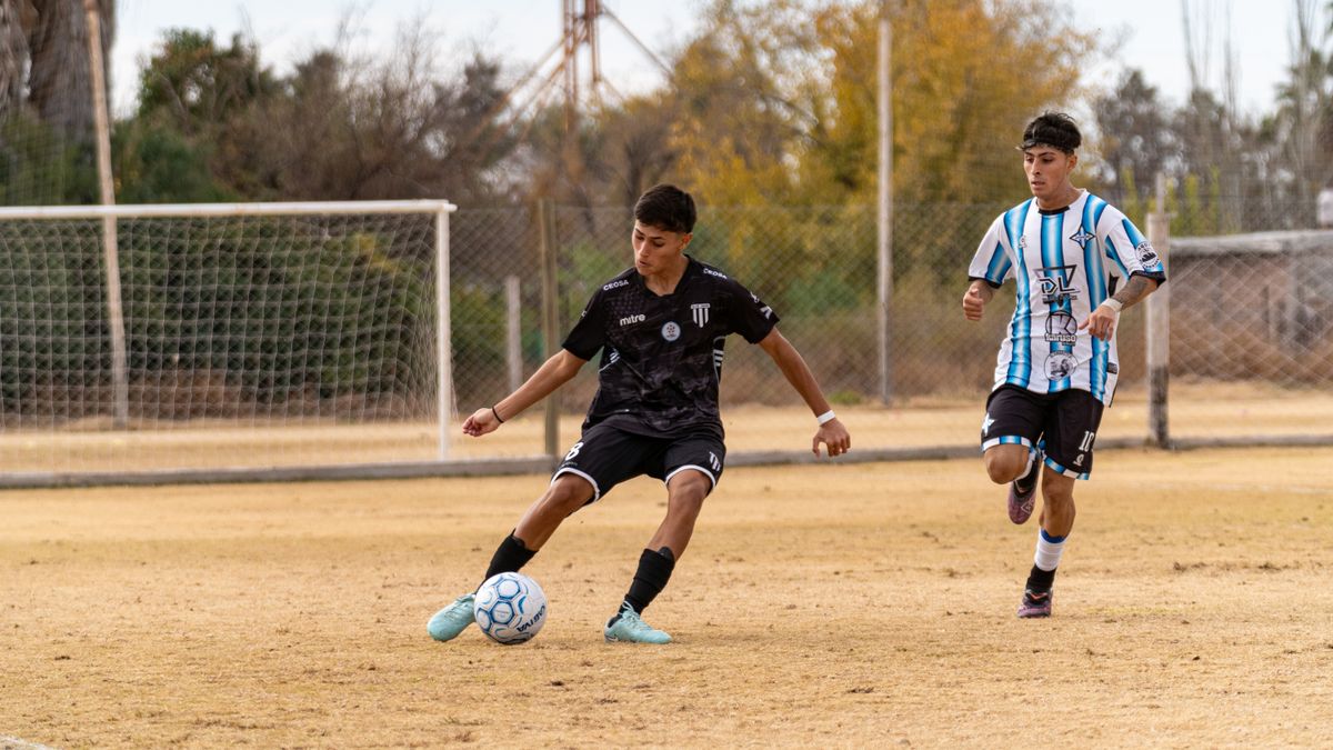 Two teenage boys playing soccer on an outdoor field, displaying skill and focus in their match.
