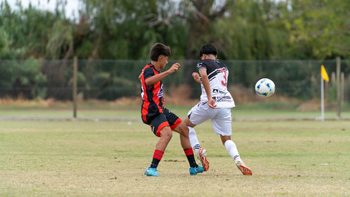 Two young soccer players compete for the ball during a match on a grassy field.