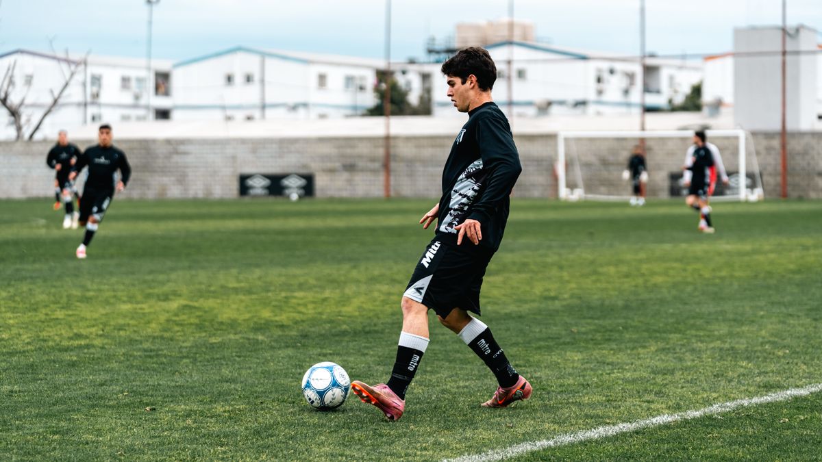 A young male soccer player in action on a grassy field during practice.