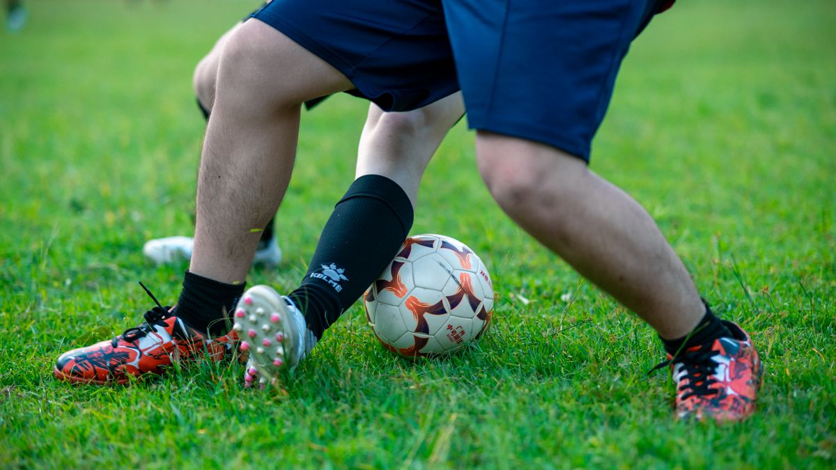 Close-up of two soccer players competing for the ball on a grassy field.
