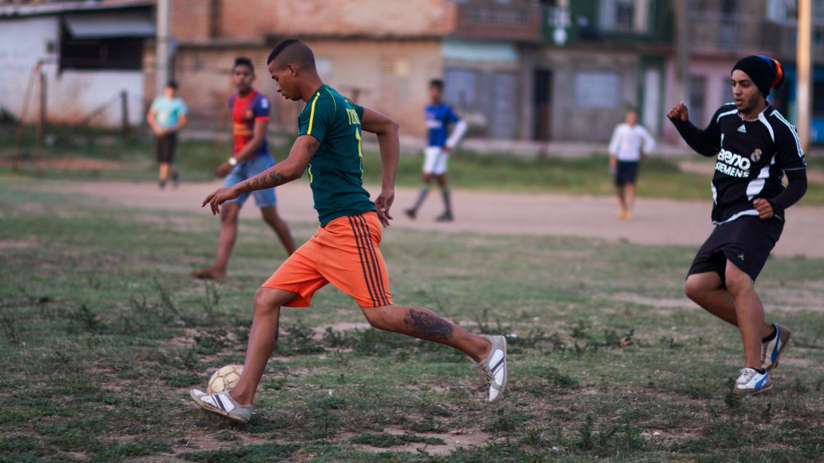 A group of young men engaged in a lively soccer game on an outdoor field. A group of young men engaged in a lively soccer game on an outdoor field.