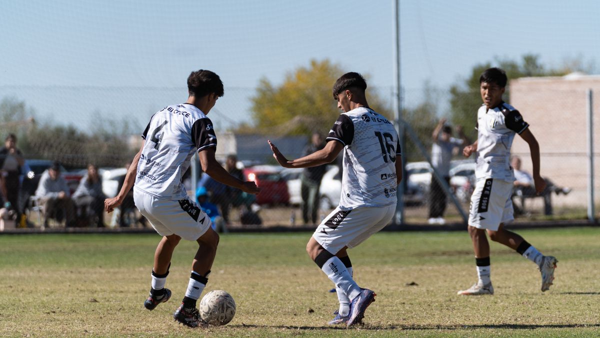 Teen soccer players competing during a daytime match on a grass field.