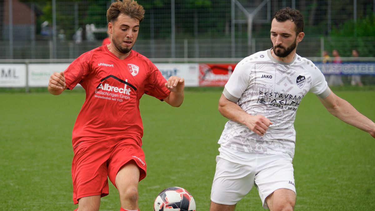 Two soccer players competing for the ball during a match on a grass field.