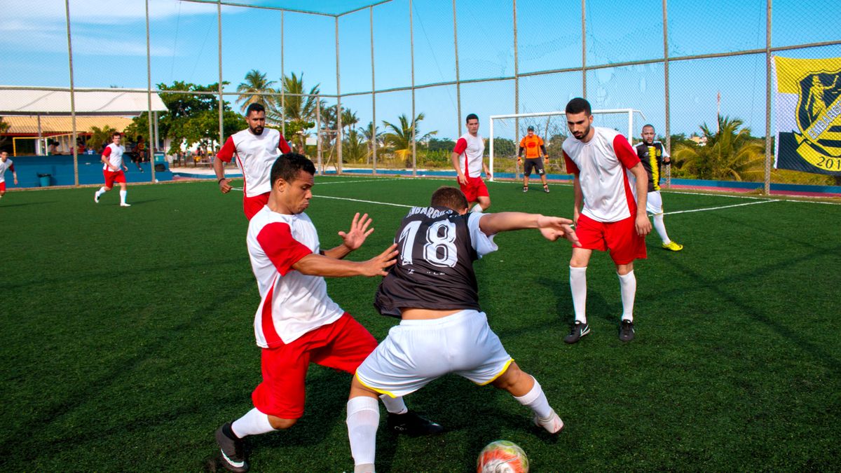 Athletes on an outdoor soccer field competing in an intense match under a clear sky.