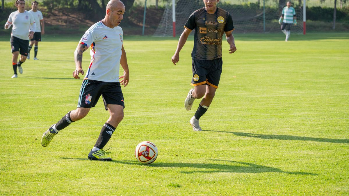 Athletes playing soccer in a competitive match on a vibrant green field.