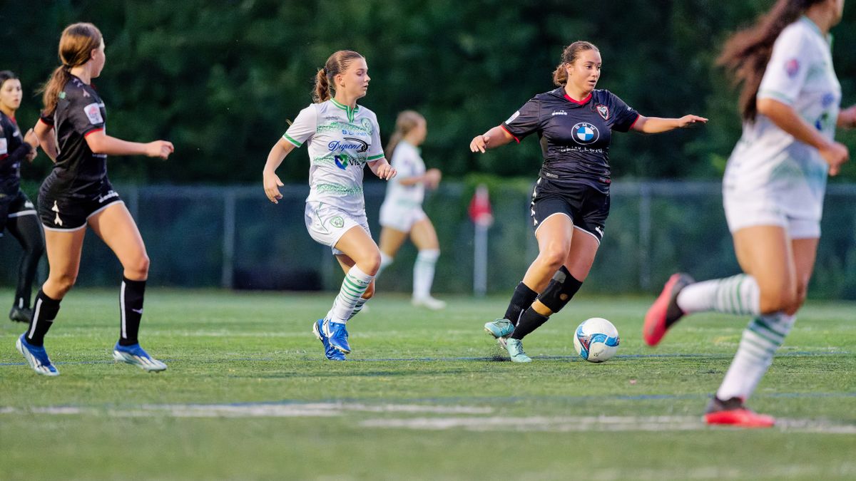 Dynamic action shot of female soccer players in motion during a game on a grass field.