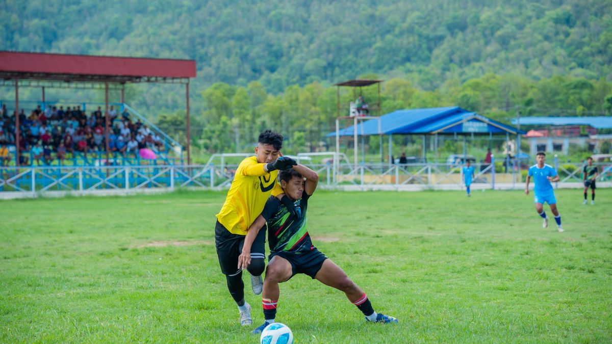 Intensity unfolds as teams compete in a vibrant village football match amidst scenic greenery.