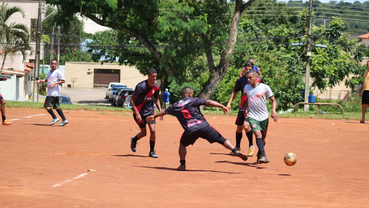 Men playing a lively soccer match on a village field under the sun. Vibrant outdoor scene.