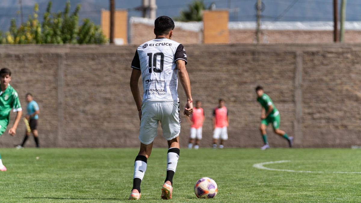 Soccer player in white jersey ready to kick the ball during a game on a sunny day.