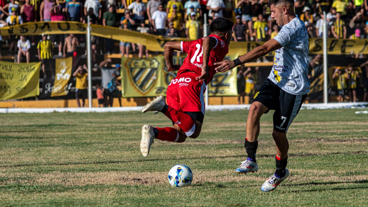 Two soccer players in action on a field, with a vibrant crowd in the background.