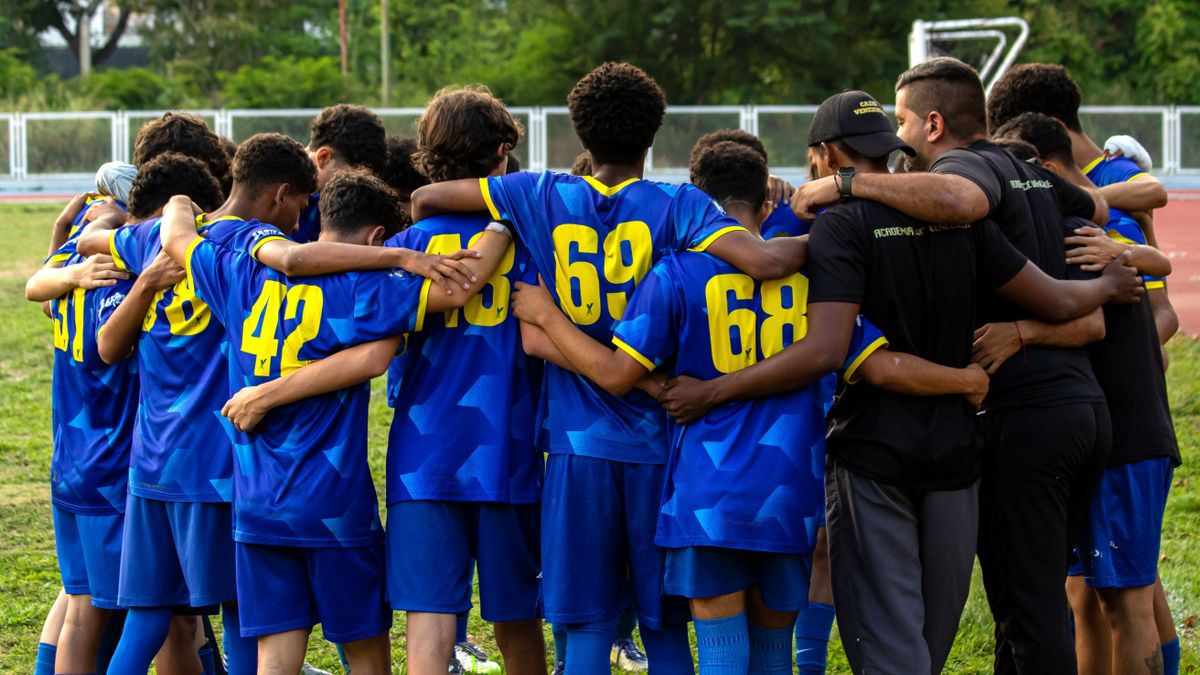A vibrant moment of unity as a youth football team huddles at a Caracas stadium. A vibrant moment of unity as a youth football team huddles at a Caracas stadium.