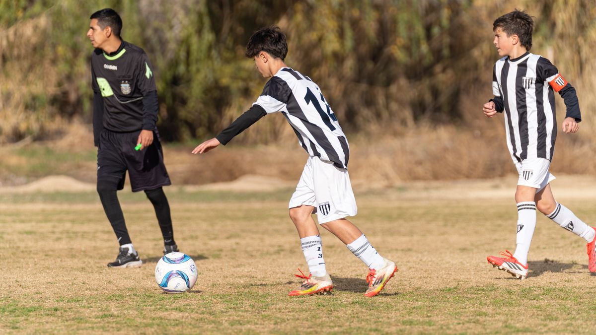 Young athletes playing soccer match outdoors on a sunny day.