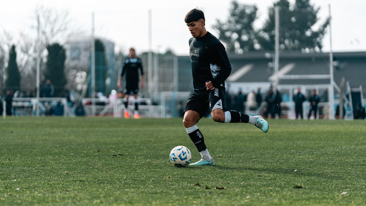 A young soccer player dribbles the ball during a daytime practice session on a grass field.