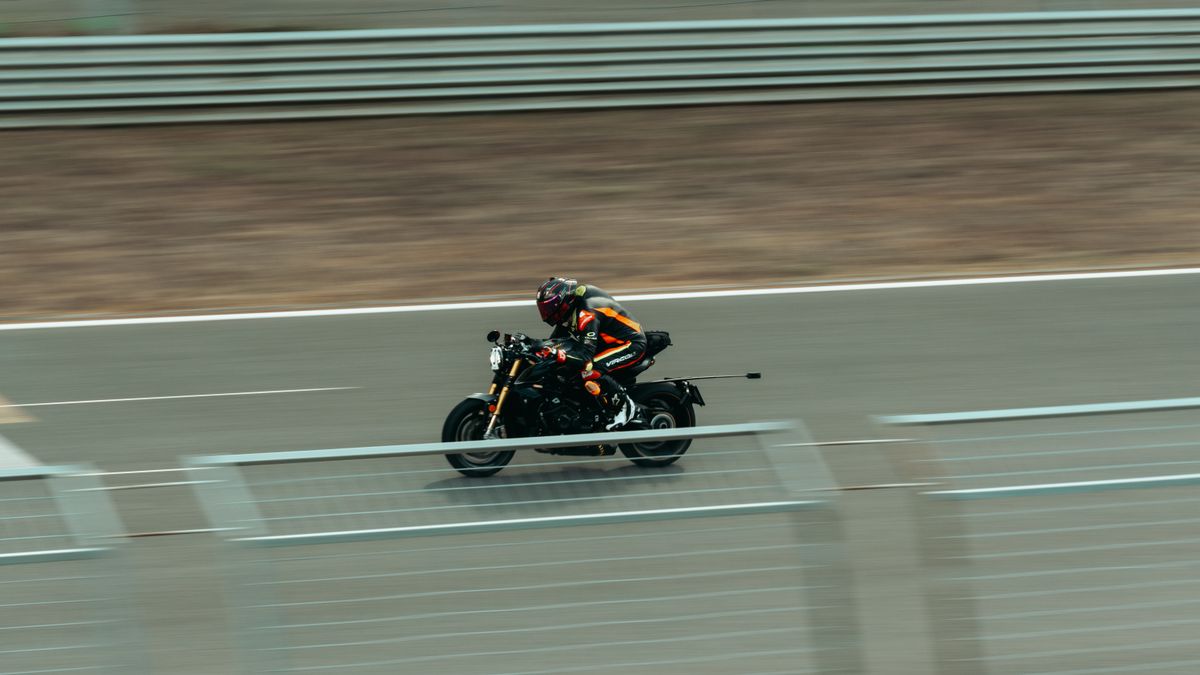 Blurred image of a motorcyclist racing at high speed on an outdoor track.