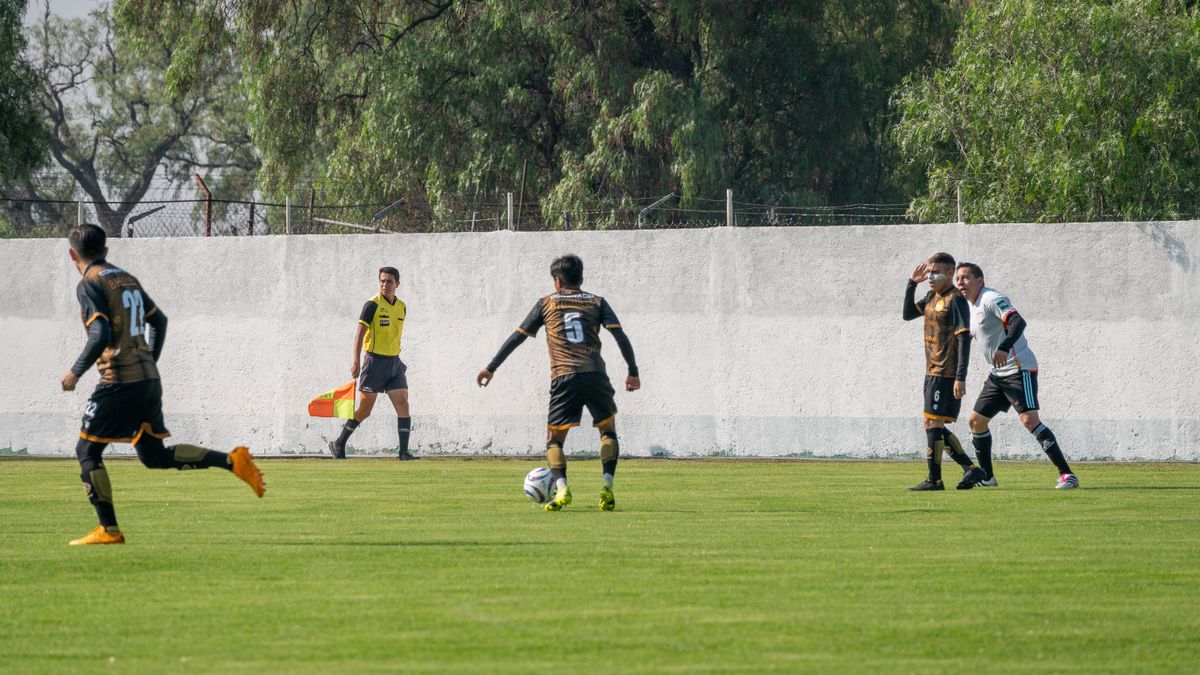 Football players actively engage in a match on a sunny day outdoors, showcasing teamwork and athleticism.