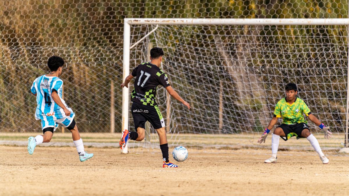 Players engaging in a high-energy soccer game with a goal attempt on an outdoor field.