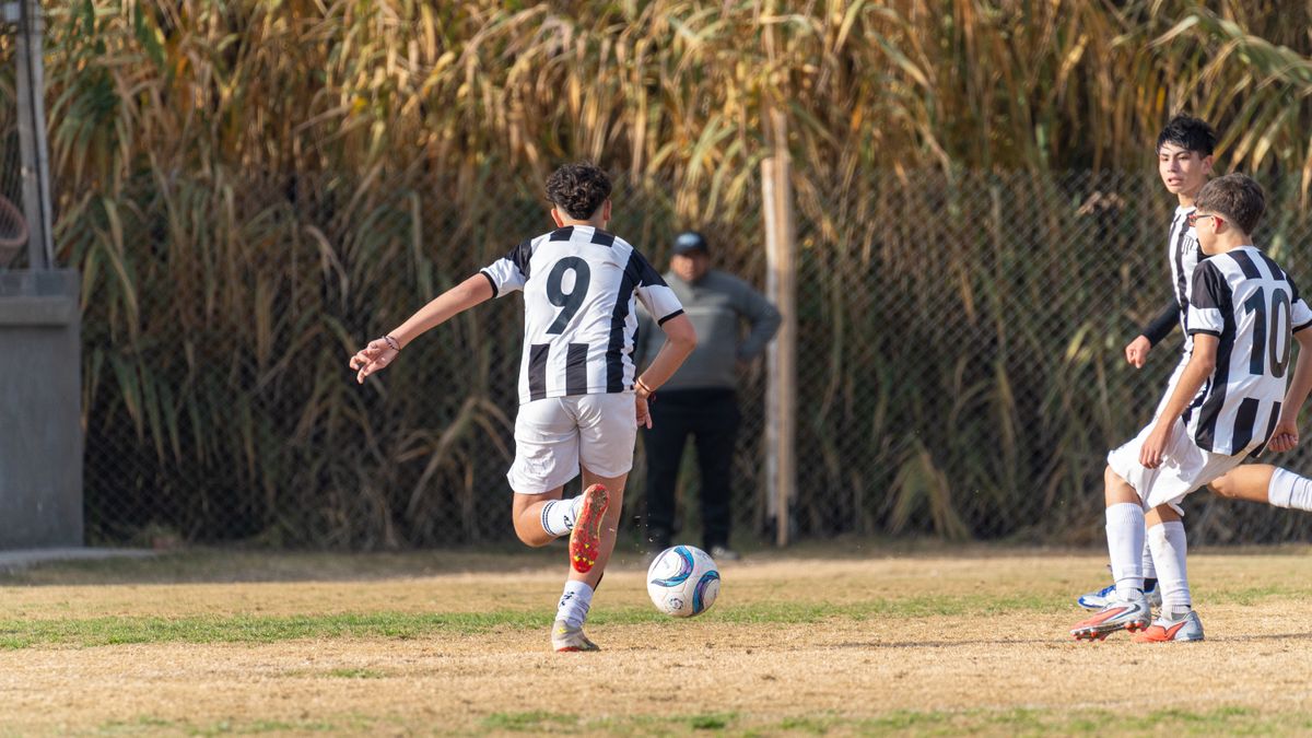Teenagers playing soccer outdoors in team jerseys, focusing on the action.