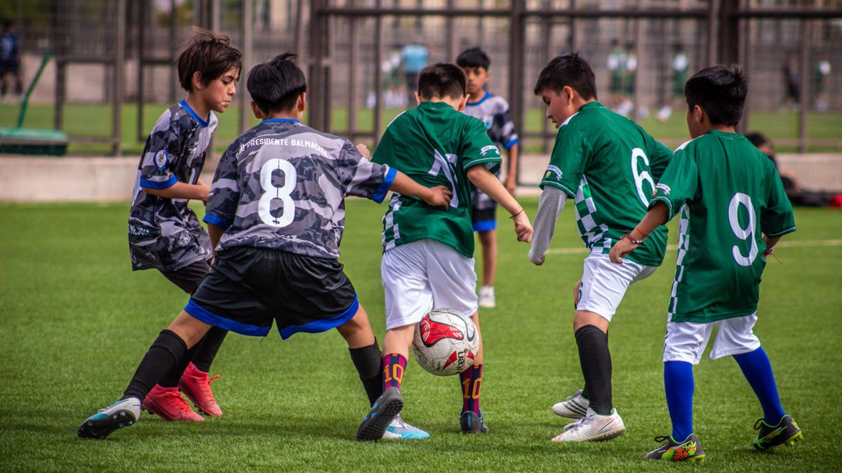 Young soccer players engaging in a dynamic football training session on a Chilean field.