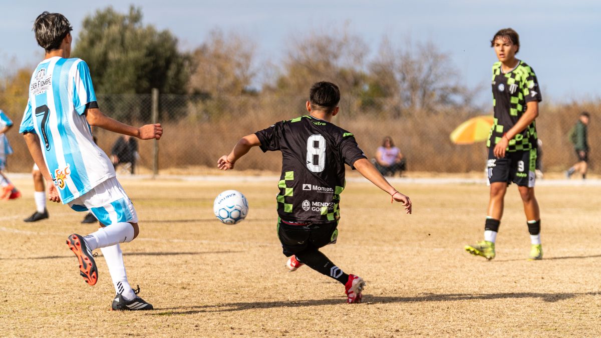 Action shot of a youth soccer match on a sunny day with players in dynamic motion.