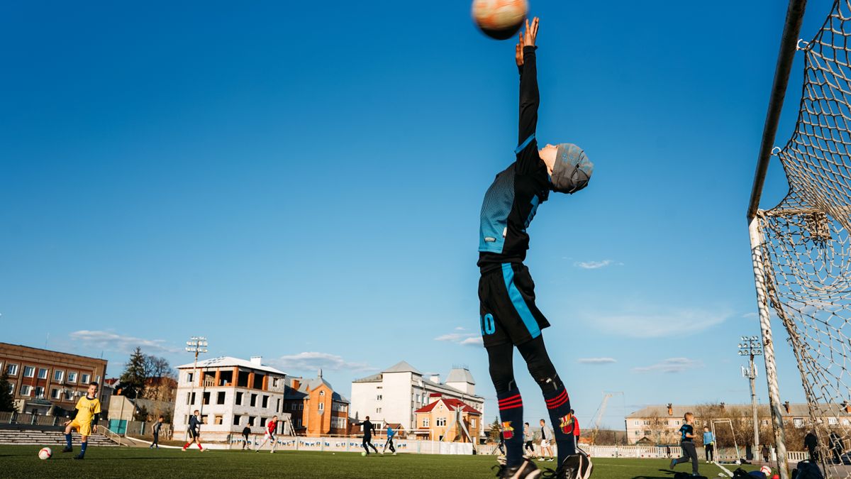 A child soccer player leaps to block a goal during an outdoor match on a sunny day. A child soccer player leaps to block a goal during an outdoor match on a sunny day.