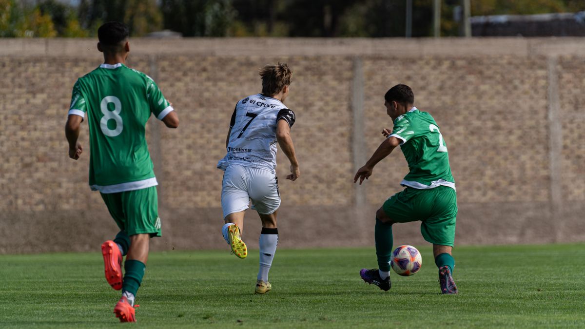 Dynamic action shot of three players competing in an outdoor soccer match.
