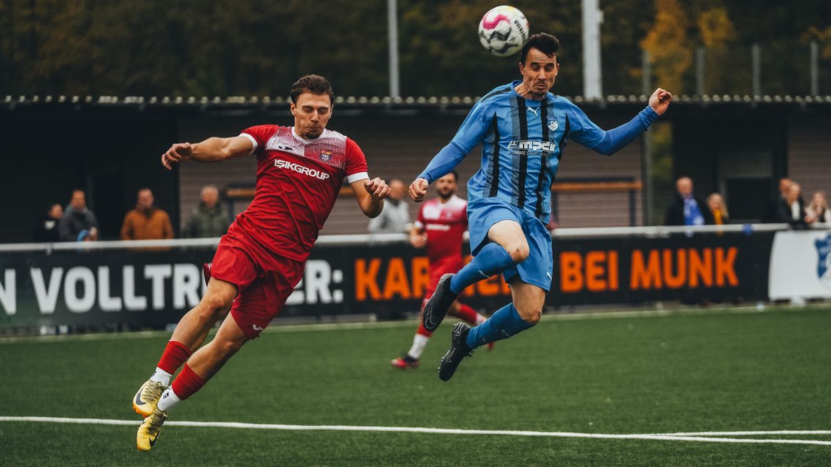 Dynamic photo of two soccer players mid-air during a competitive match.