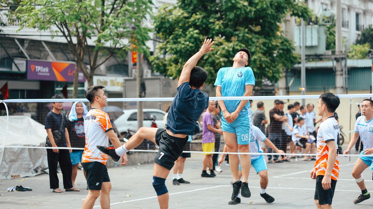 Men playing an intense volleyball game outdoors in a bustling urban area. Men playing an intense volleyball game outdoors in a bustling urban area.