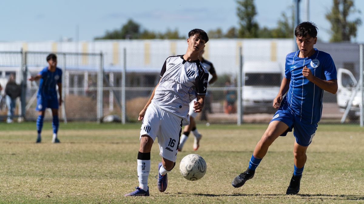 Teen soccer players in dynamic action during an outdoor match on a sunny day.
