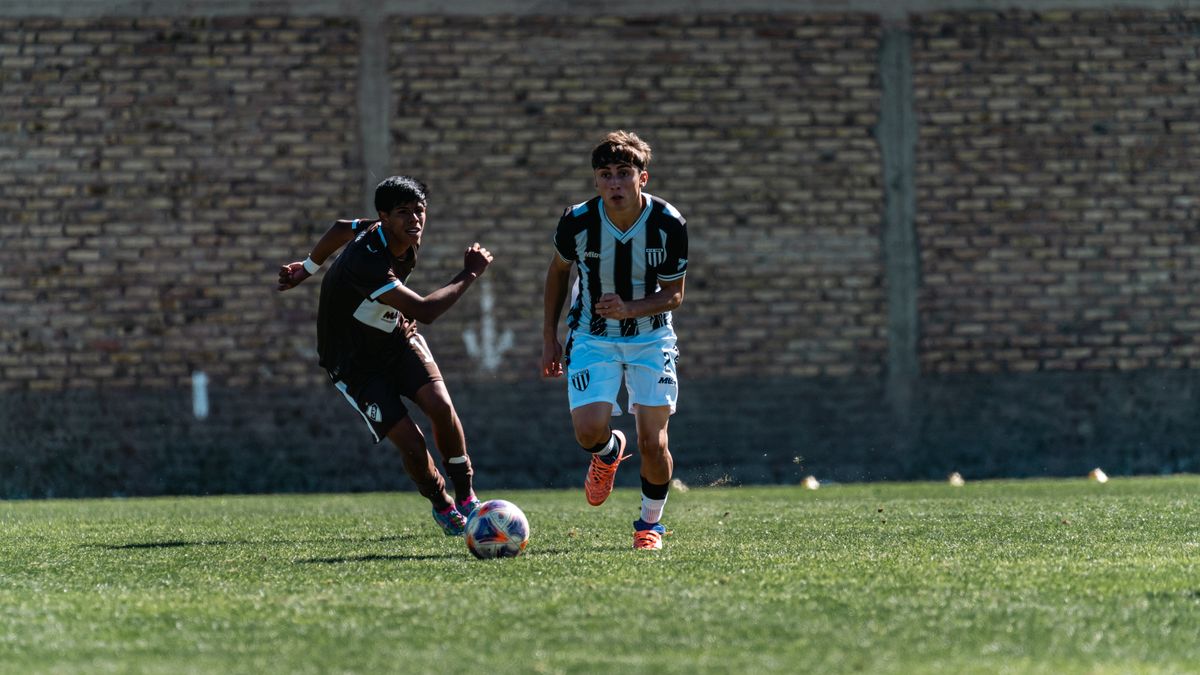 Two players engage in a dynamic soccer game outdoors on green field.