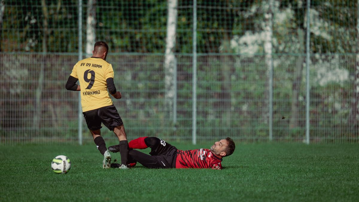 Two soccer players in action with a dramatic tackle on a grassy field during a match.
